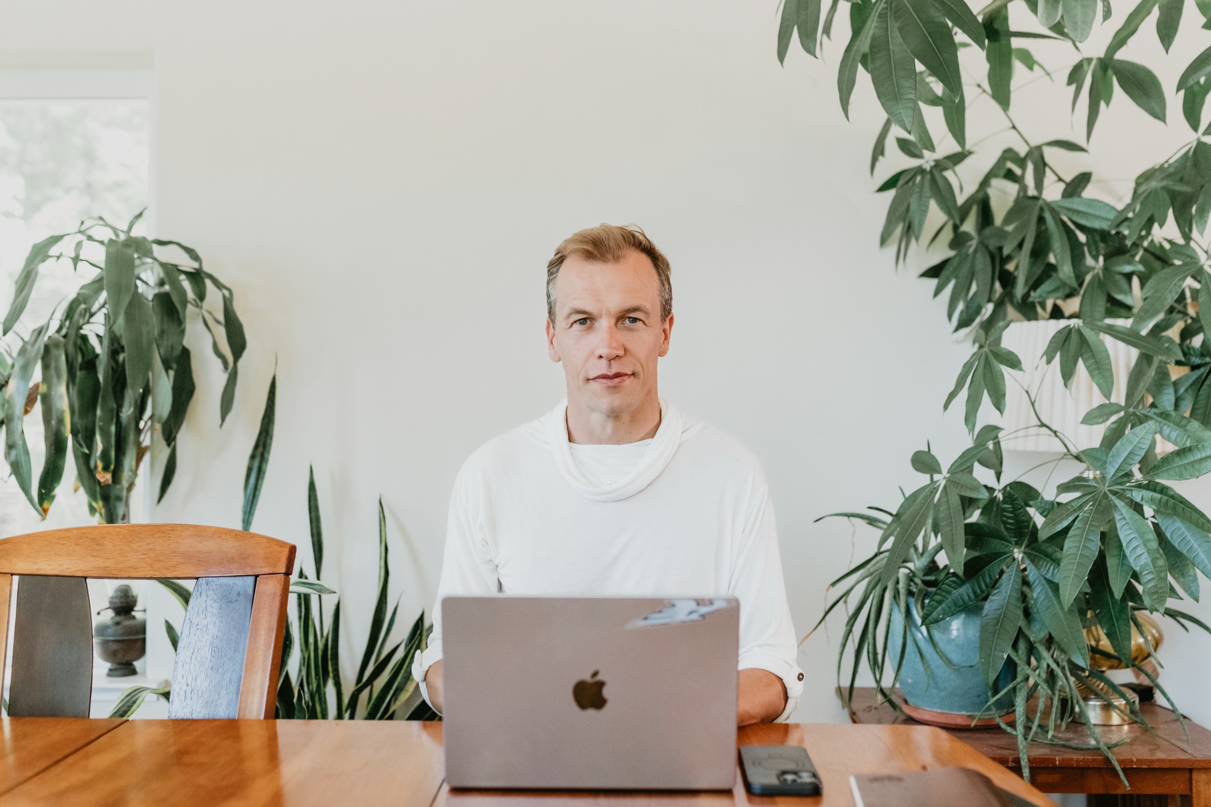 Nick Tong at his desk, laptop and warm plants around him